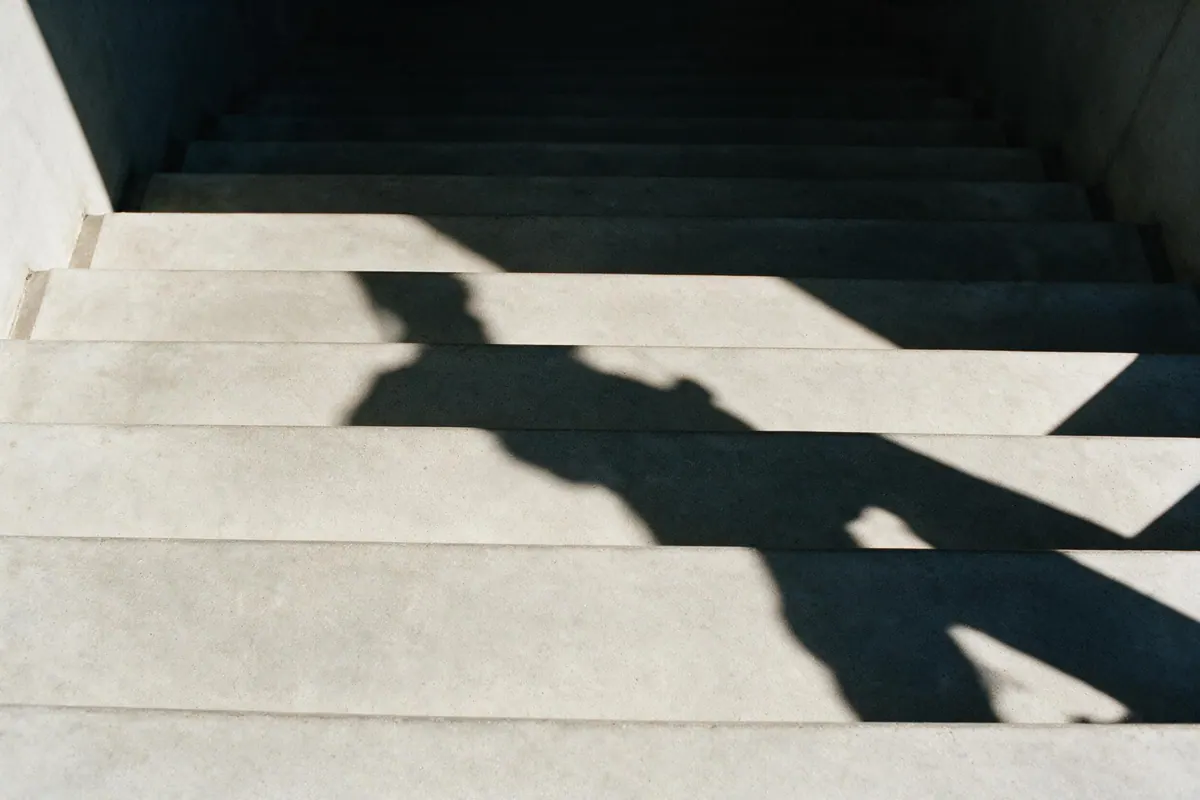 A wide concrete staircase seen from above, clean repeating treads with a shadow falling across them.