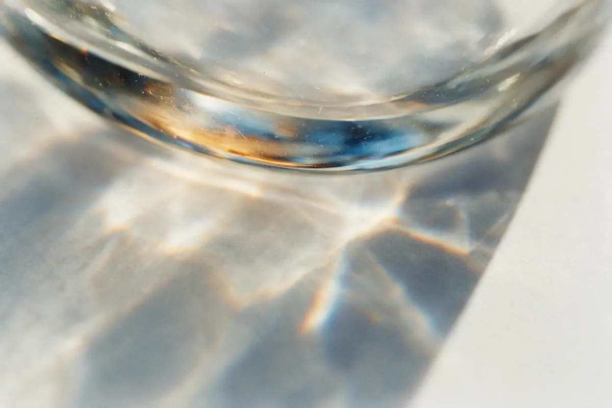 Light refracting through the thick edge of a piece of glass, splitting into warm and cool caustics.